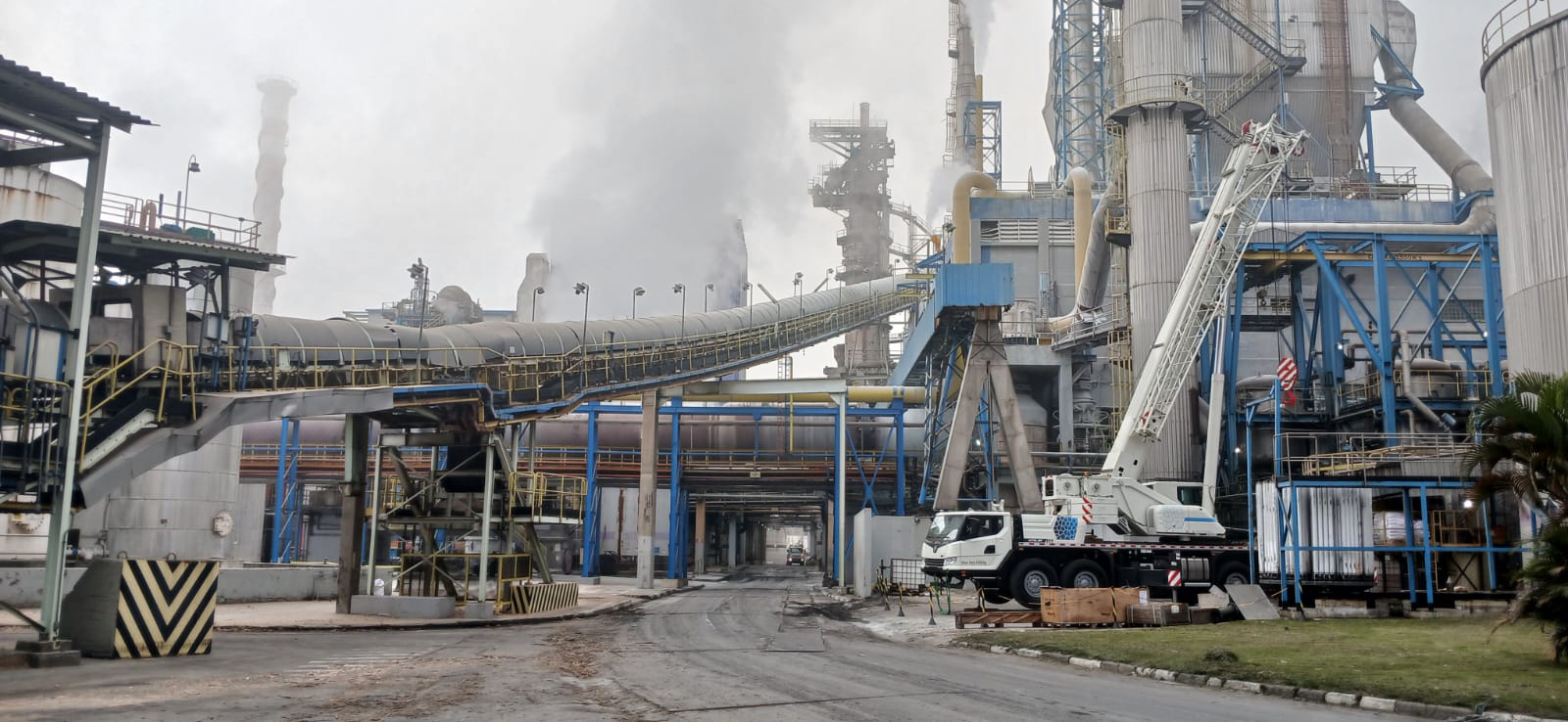 Guindaste posicionado em complexo industrial para serviço de içamento de carga.