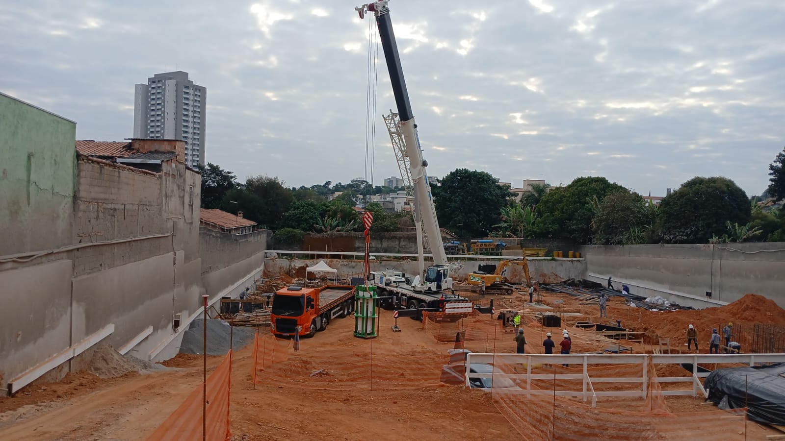 Guindaste realizando a carga de um caminhão em um canteiro de obras.
