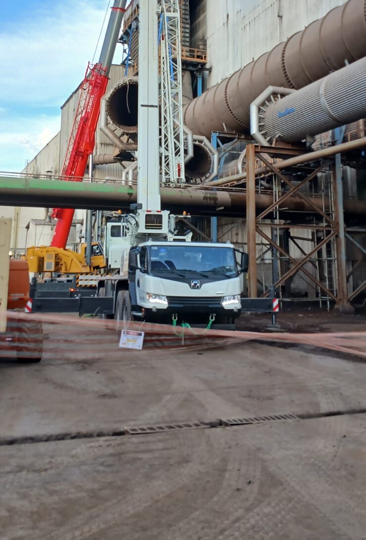 Guindaste branco em operação durante parada para manutenção em complexo industrial.